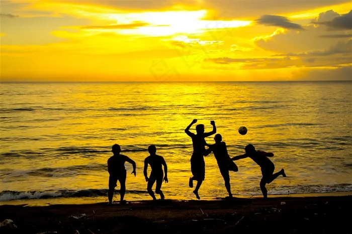 夕阳下的在海边踢球的孩子们