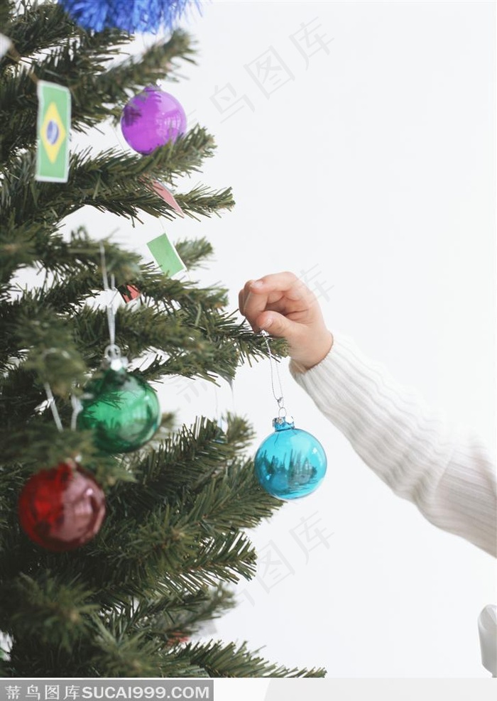 一只装扮圣诞树的手与漂亮的圣诞小彩球