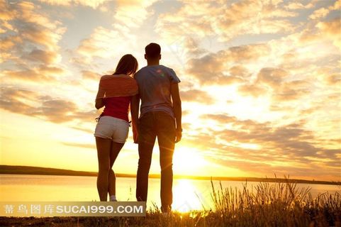 晚霞下站在海边的情侣高清摄影图片