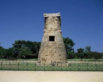 蓝天下树林前铁艺护栏里的古碉堡