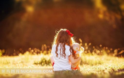 草地上抱着洋娃娃的小女孩