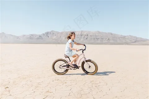 沙滩上骑自行车的小女孩