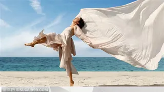 穿白色抹裙飘扬的披肩单脚腾空在沙滩上跨越