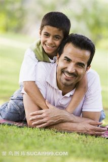 中东爬在草地上玩耍的父子摄影素材