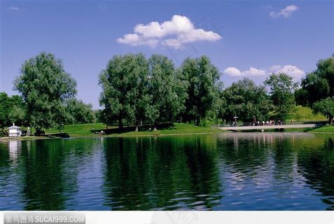 白云下的湖水、树木和桥上的游客