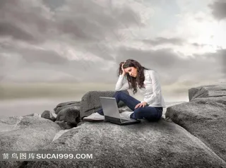 坐在岩石上看着笔记本的美女