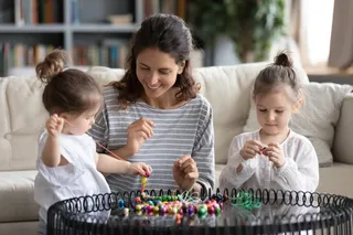 亲子互动母亲陪伴双胞胎女儿做串珠