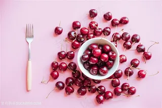 粉色背景一碗樱桃散落在桌上