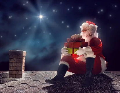 抱着礼盒坐在屋顶上的圣诞老人