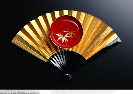 一把金色的折扇和一个精致的陶瓷盘