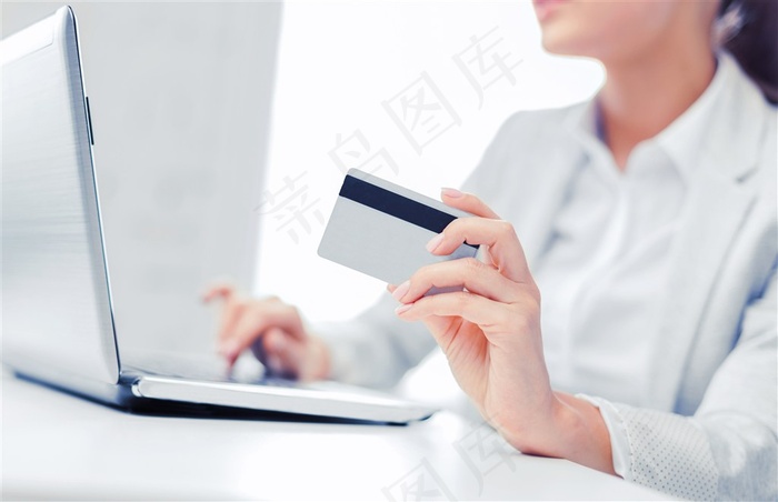 拿着白色信用卡在电脑上操作的女性高清图片