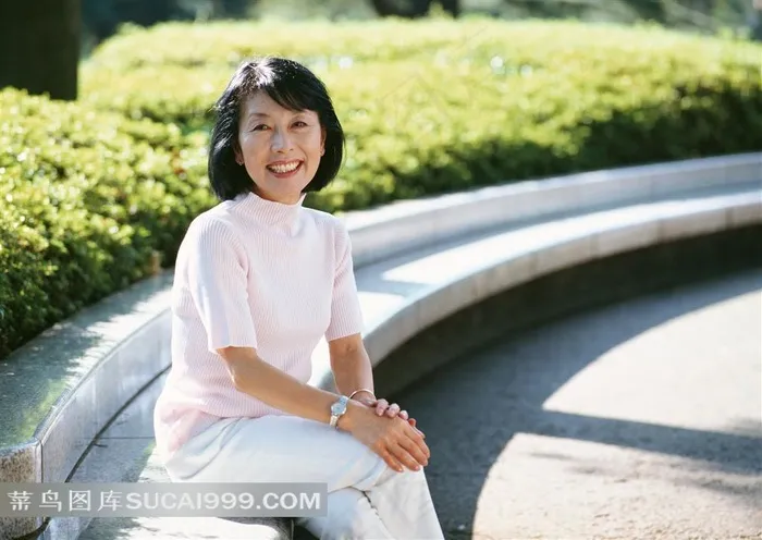 坐在花坛边微笑的女性老人