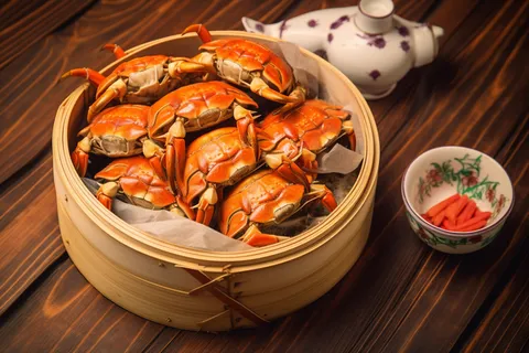 餐桌蒸笼屉里的螃蟹和茶壶摄影图