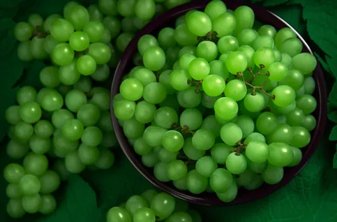 一个装有绿葡萄的碗放在桌子上的摄影图