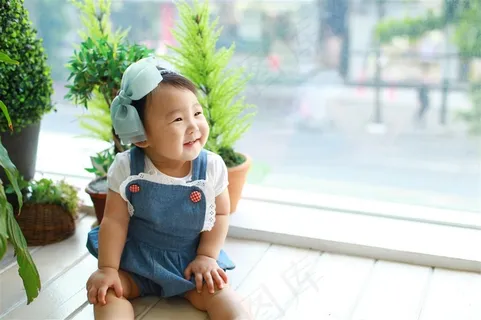 坐在窗口旁边微笑的可爱幼儿 坐在窗口旁边微笑的可爱幼儿