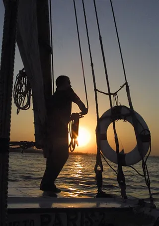 夕阳西下时海面渔船上的打渔人