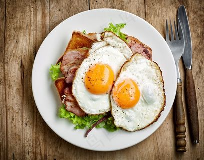 两个煎蛋和培根在白色盘子里的高清摄影图片