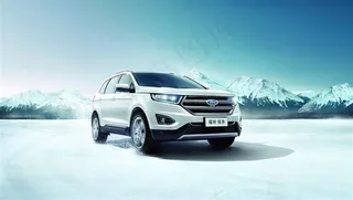 行驶在雪山下结冰路面的美国福特锐界城市型越野车