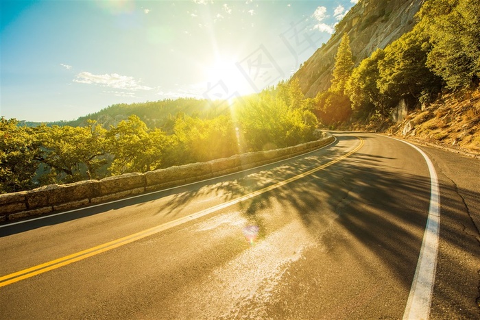 阳光下山腰间的公路高清摄影图