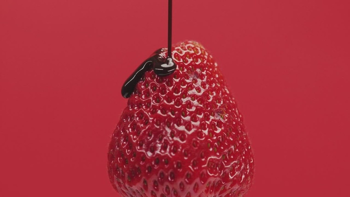 在红色背景上用巧克力糖浆覆盖草莓。