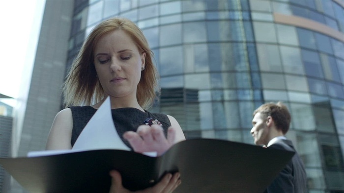 在有风的街道上看文件的女人