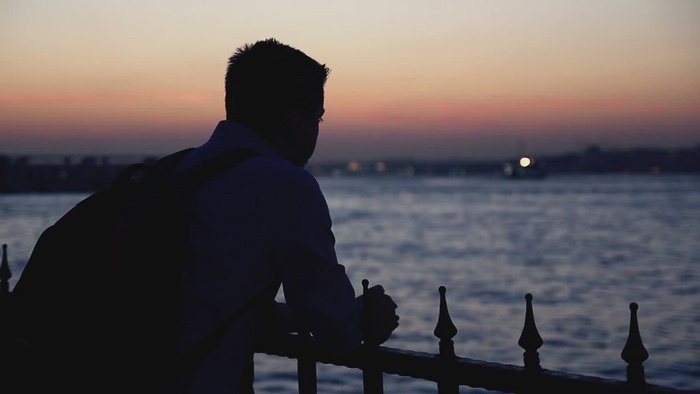 一个孤独的人的剪影黄昏的在河附近