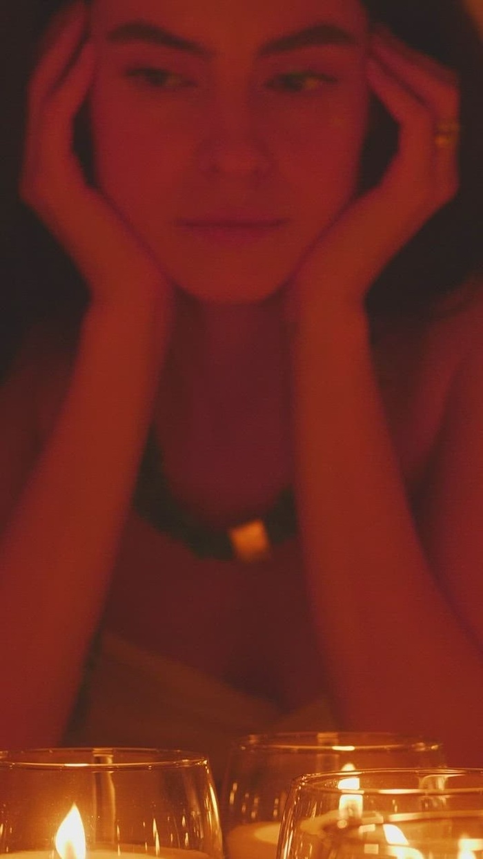 一位年轻的精神女性在黑暗的地方欣赏一些燃烧的蜡烛的沉思脸。