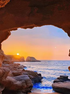 海边被初升的太阳照耀的山洞