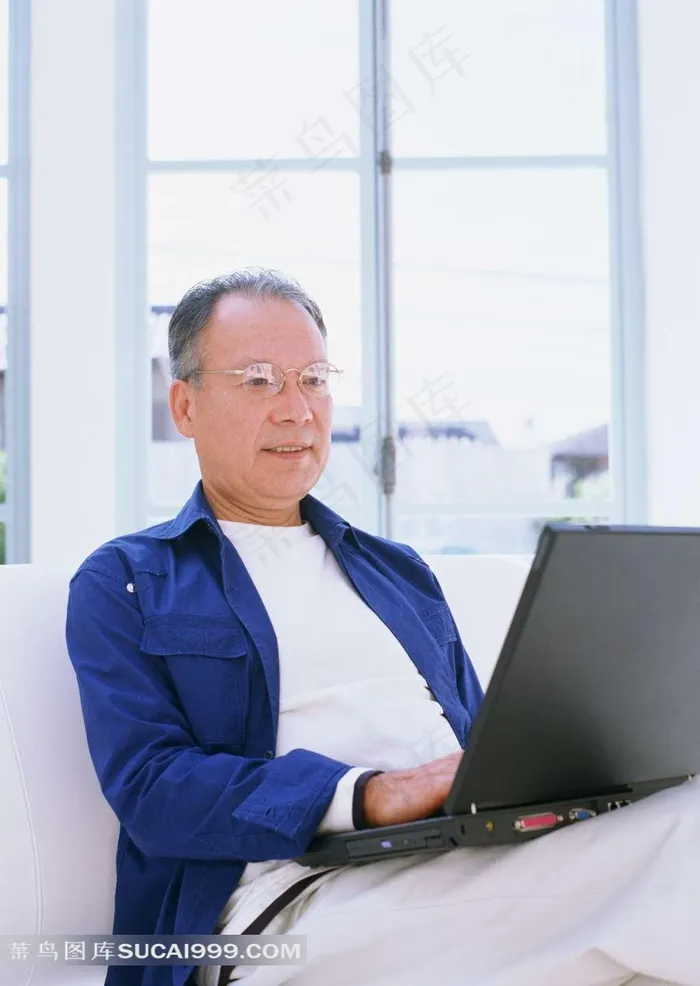 坐在沙发上看电脑上网的老年男人