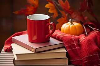 秋冬公园长椅堆放的书籍红色咖啡杯和红色针织围巾摄影图