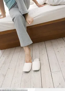 正在下床穿拖鞋的女人的腿部特写