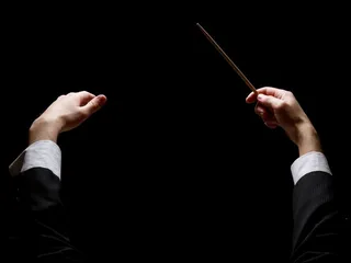 黑色背景上拿着指挥棒的指挥家高清图片