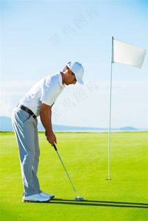 草坪上打高尔夫球的男士和旗杆高清图片