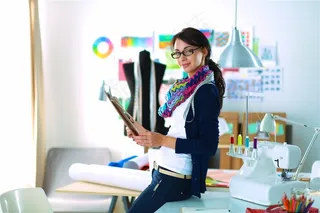 侧身坐在办公桌上的服装设计师