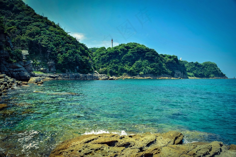 碧海蓝天下的翠绿岛屿灯塔