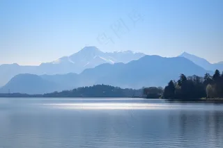 阳光下波光粼粼的湖面山峰摄影图