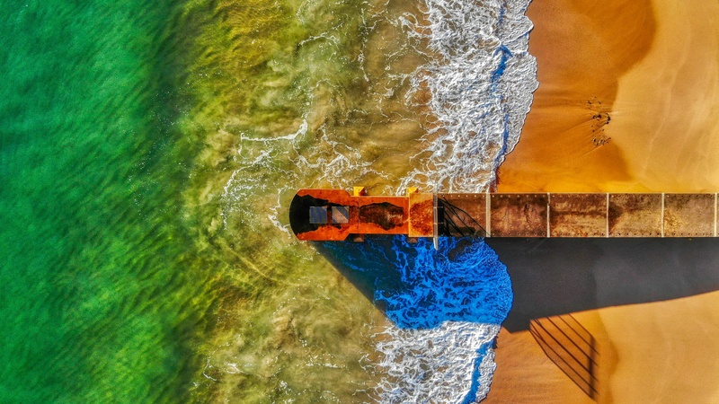 航拍碧海金沙与码头交汇图