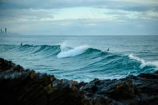 海浪中的冲浪者与远方的城市天际线