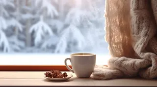 冬季窗外下雪白雪飘窗喝咖啡温暖毛衣摄影图