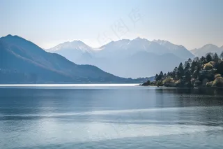 阳光下波光粼粼的湖面山峰摄影图