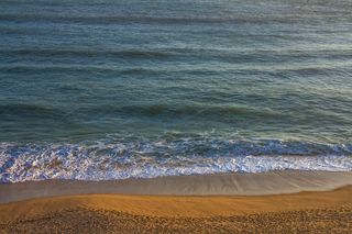 温暖阳光下的金色沙滩与波涛