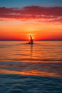 夕阳落日下海洋海面帆船余晖倒影美景摄影图