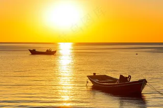 夕阳落日下的海洋湖面小船余晖倒影摄影图