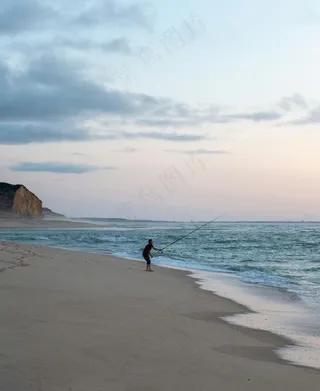 黄昏海滩上的孤独垂钓者