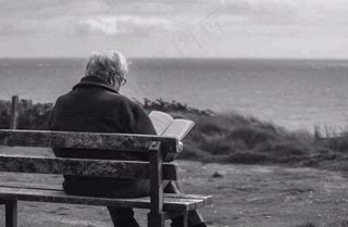 黑白简约坐着海边长椅看书的老人白发重阳节父亲节摄影图