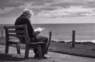 黑白简约坐着海边长椅看书的老人白发重阳节父亲节摄影图