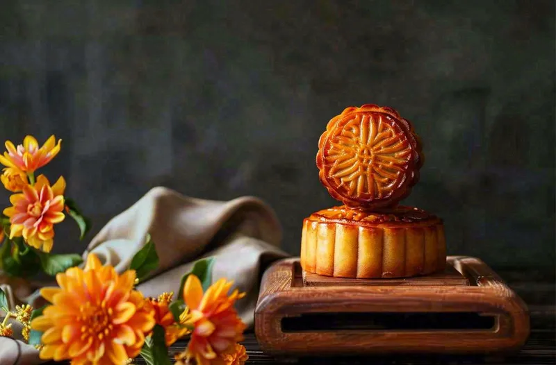 中国传统美食月饼中秋节菊花摆盘黑色背景摄影图(1360x896)