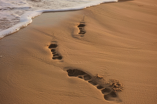 海滩上的脚印浪花摄影图