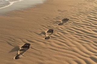 海滩上的脚印浪花摄影图