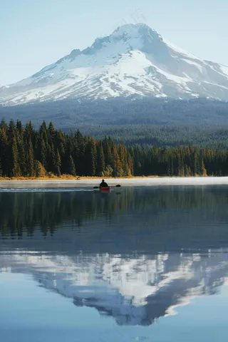 宁静湖面上的独舟与倒映的雪山